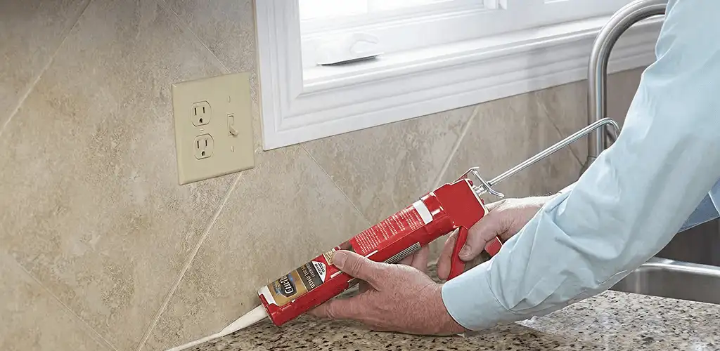 Handyman applying caulk along a kitchen backsplash and countertop seam in Tucson, AZ