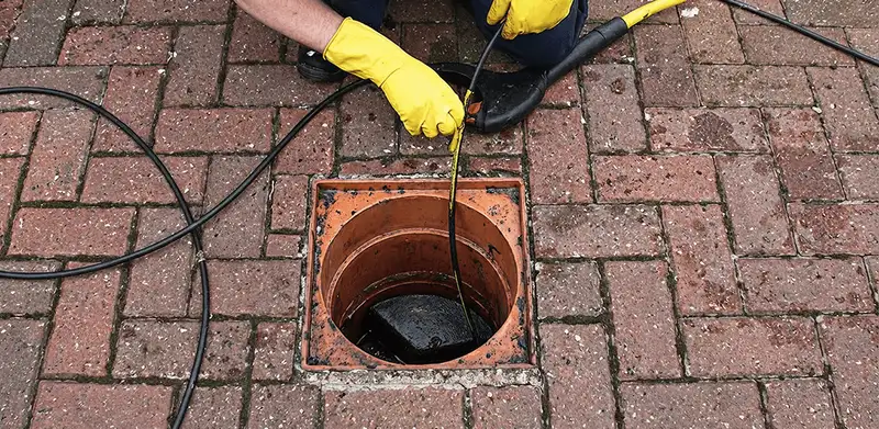 Drain cleaning technician using a drain snake to clear a clogged drain in Tucson, AZ