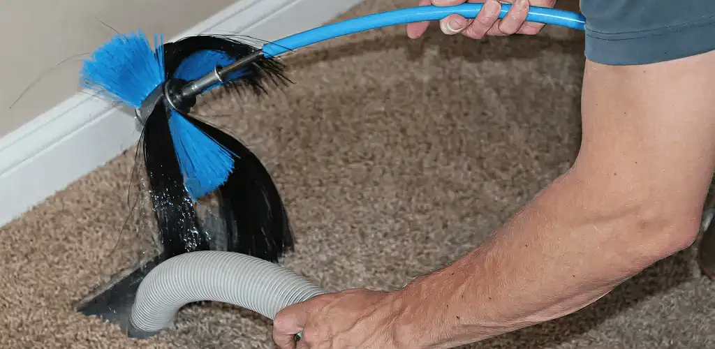 Dryer vent cleaning technician brushing lint from a vent line in Tucson, AZ