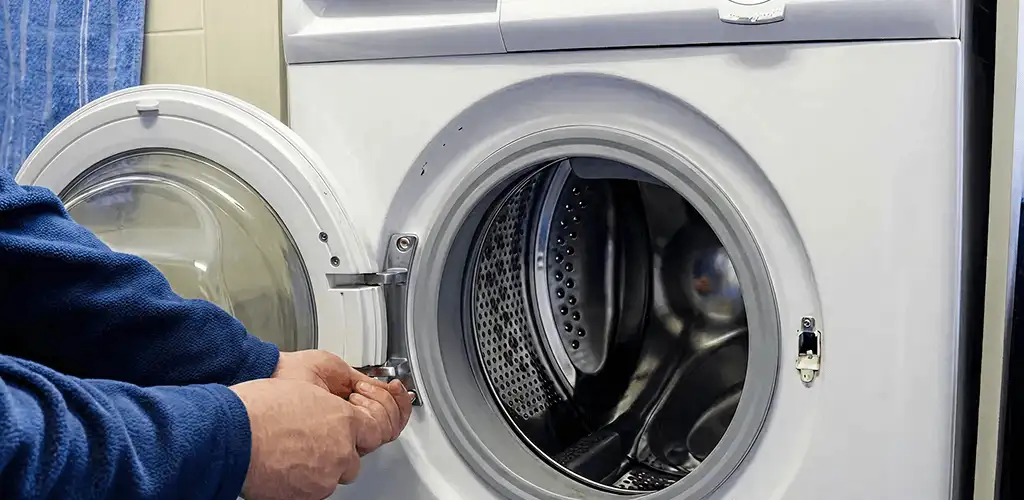 Washing machine repair handyman checking a front-load washer door and latch in Tucson, AZ