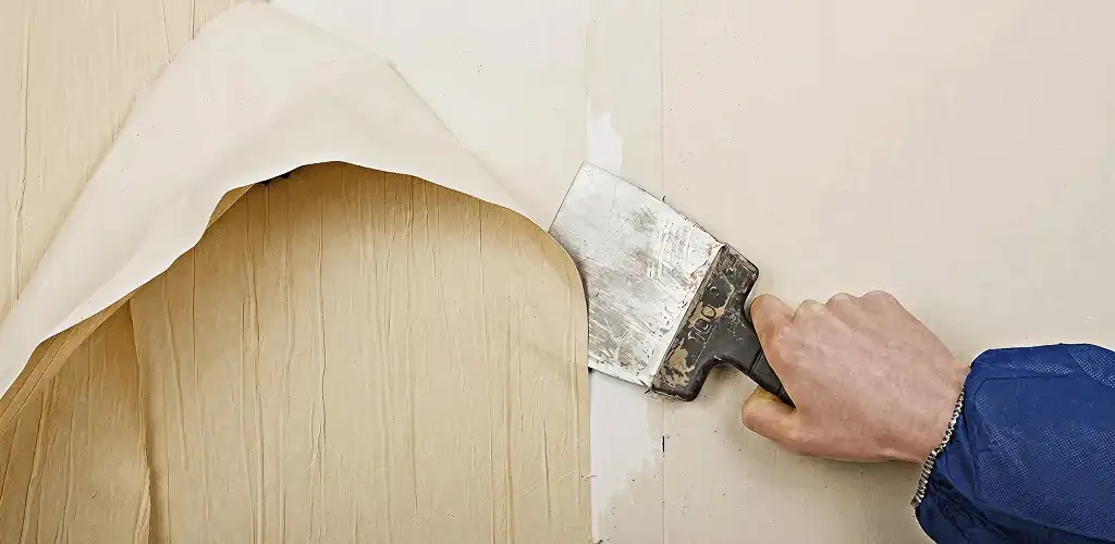 Handyman removing wallpaper with a scraper for wall preparation in Tucson, AZ