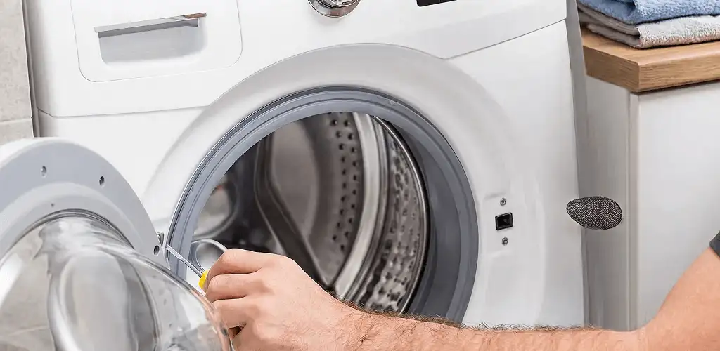 Handyman repairing a front-load washing machine and inspecting the drum in Tucson, AZ