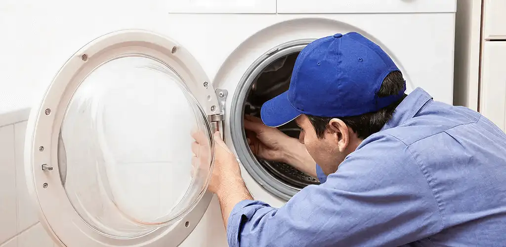 Washing machine repair handyman inspecting a front-load washer drum in Tucson, AZ