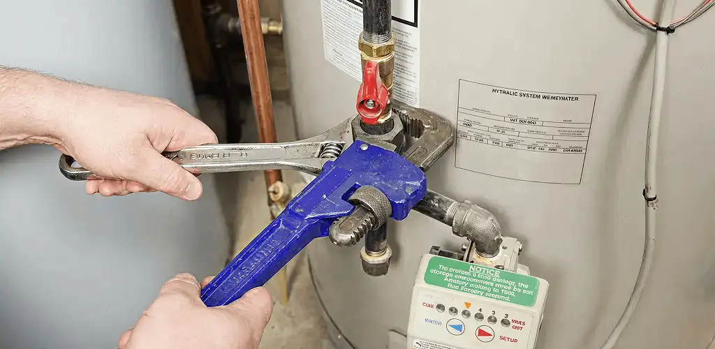 Water heater repair technician tightening the shutoff valve and supply line in Tucson, AZ